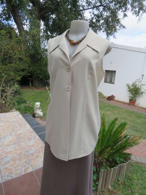 As new sleeveless cream top closing with 2 buttons and open collar. By SMILEY`S size 40/16.