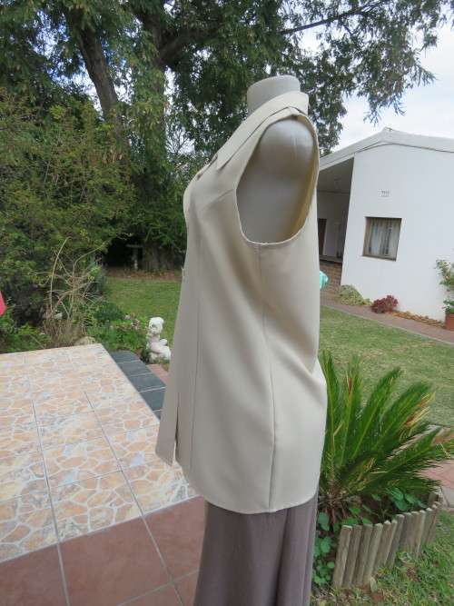 As new sleeveless cream top closing with 2 buttons and open collar. By SMILEY`S size 40/16.