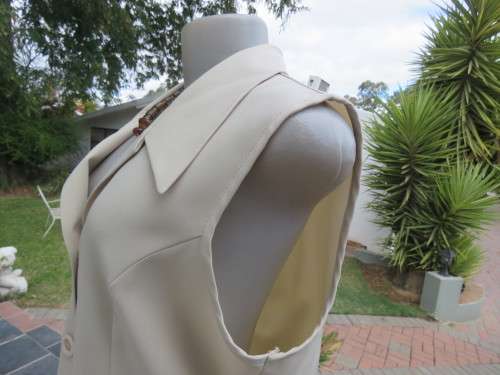 As new sleeveless cream top closing with 2 buttons and open collar. By SMILEY`S size 40/16.
