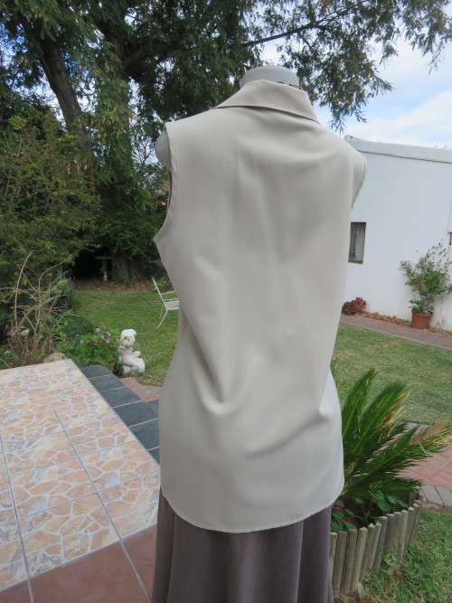 As new sleeveless cream top closing with 2 buttons and open collar. By SMILEY`S size 40/16.