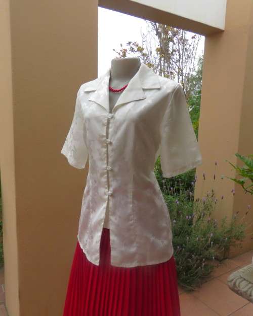 Shiny light cream tailored polyester satin short sleeve top with embossed patterns.Size 38/14.As new