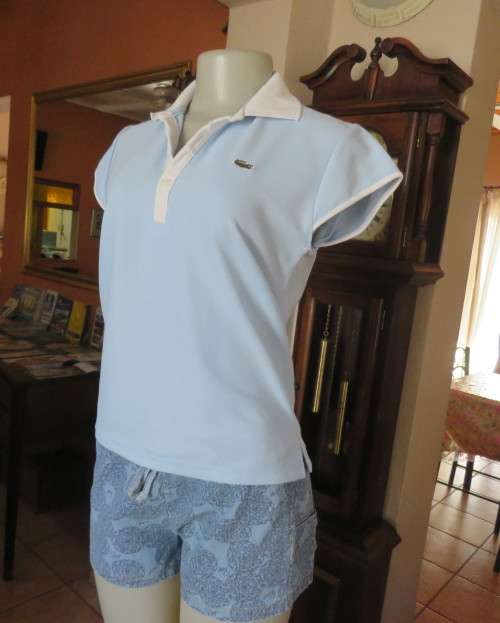 LACOSTE light blue top with white knitted collar and edging.Size 34 to 36.Opening in front.Good cond