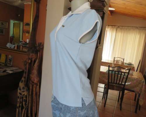 LACOSTE light blue top with white knitted collar and edging.Size 34 to 36.Opening in front.Good cond