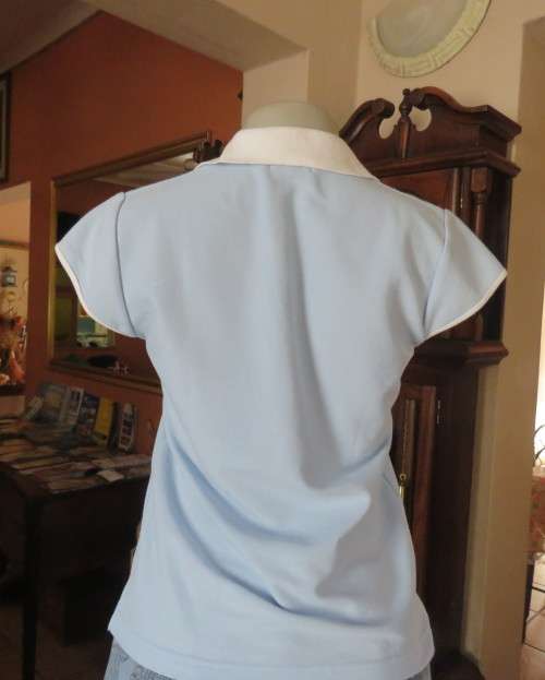 LACOSTE light blue top with white knitted collar and edging.Size 34 to 36.Opening in front.Good cond
