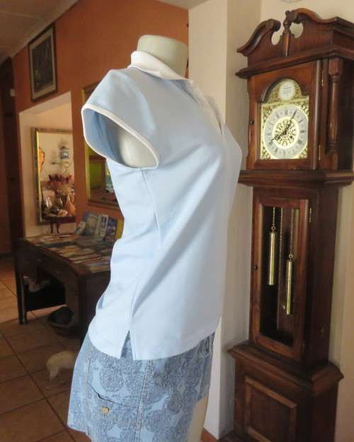 LACOSTE light blue top with white knitted collar and edging.Size 34 to 36.Opening in front.Good cond