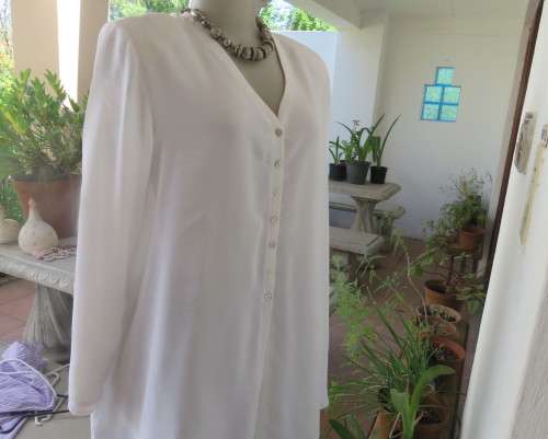 Embossed white loose cut button down V neck top with long sleeves.Size large 40. As new in polyester