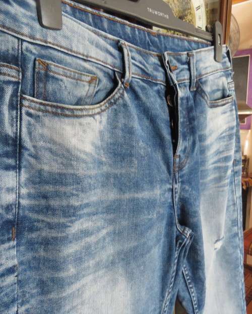 INDIGO USA Denim Co. Men`s jeans with skinny legs in distressed look. Size 34.Close with buttons.