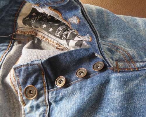 INDIGO USA Denim Co. Men`s jeans with skinny legs in distressed look. Size 34.Close with buttons.