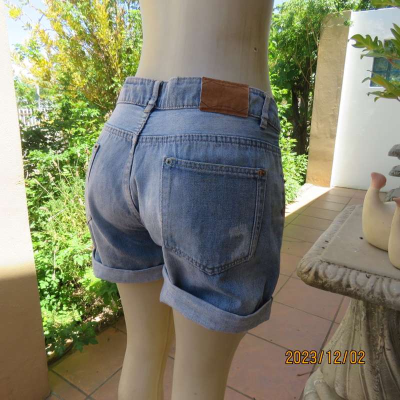 Distressed look denim shorts size 38/14 with turnover legs. Buttoned fly. Pockets back/front.