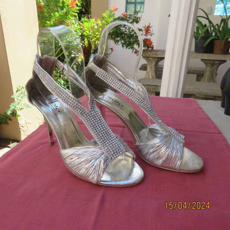 Pair of silver high heel SOLO size 6 open toe sandals. Zip at back. FAUX diamond straps. Used once.