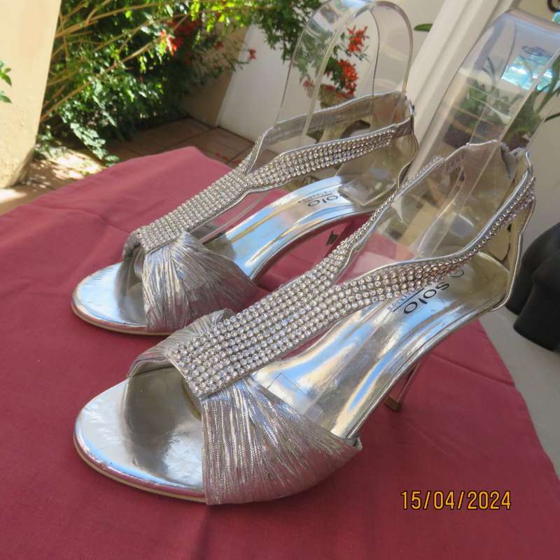 Pair of silver high heel SOLO size 6 open toe sandals. Zip at back. FAUX diamond straps. Used once.