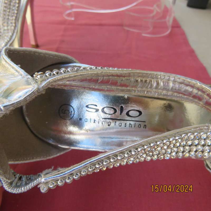 Pair of silver high heel SOLO size 6 open toe sandals. Zip at back. FAUX diamond straps. Used once.
