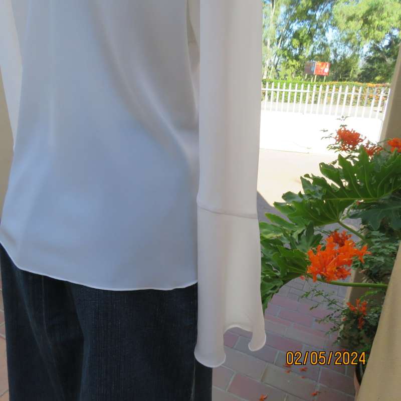 Pretty white polyester slip over top with long sleeves/flare cuffs. Front braided opening.Size 38/40