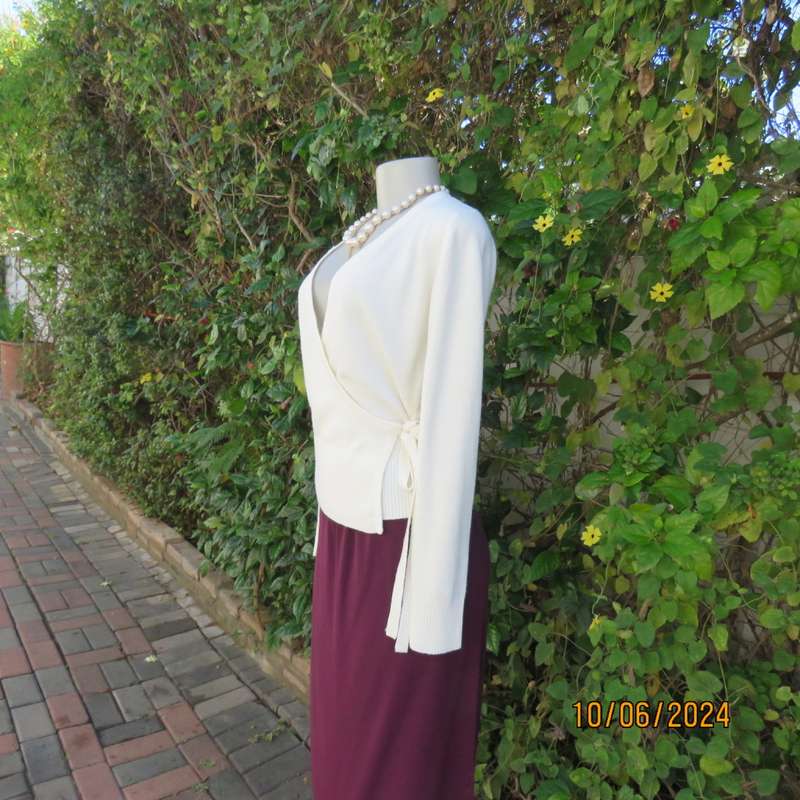 Soft cream foldover acrylic knit top with long sleeves. Straps at side to tie. Decoration left. 34.