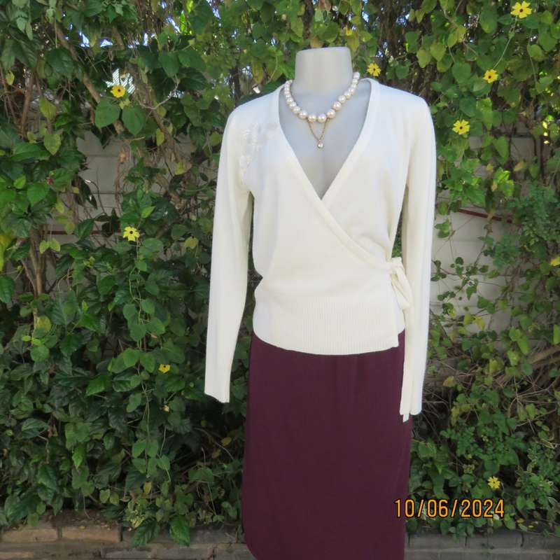 Soft cream foldover acrylic knit top with long sleeves. Straps at side to tie. Decoration left. 34.
