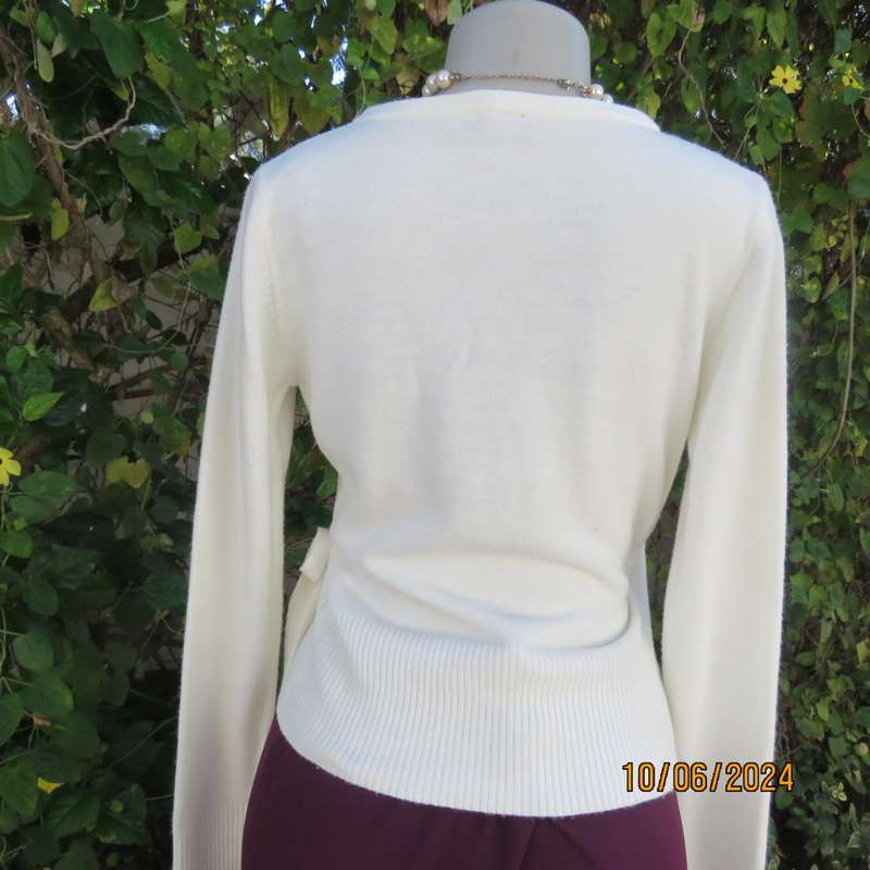 Soft cream foldover acrylic knit top with long sleeves. Straps at side to tie. Decoration left. 34.