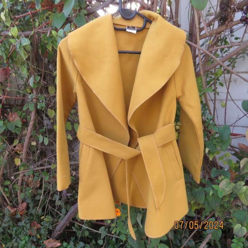 Mustard colour fold over warm jacket for 9 to 10 yr old girl. By IQ. Two pockets. Band around waist.