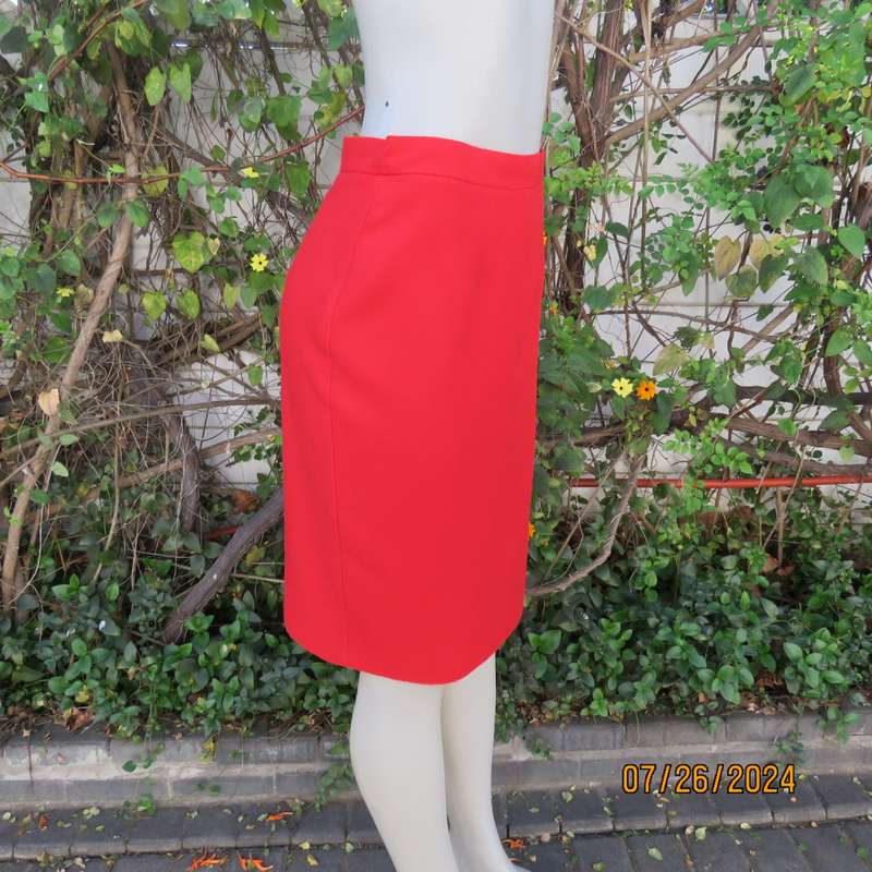 Bright red knee length lined pencil skirt in poly/viscose. By KELSO Petite size 35.Back zip/pleat.
