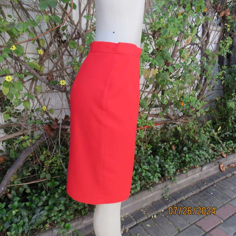Bright red knee length lined pencil skirt in poly/viscose. By KELSO Petite size 35.Back zip/pleat.