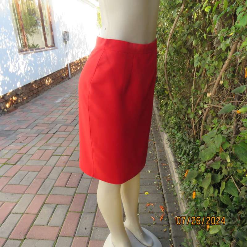 Bright red knee length lined pencil skirt in poly/viscose. By KELSO Petite size 35.Back zip/pleat.