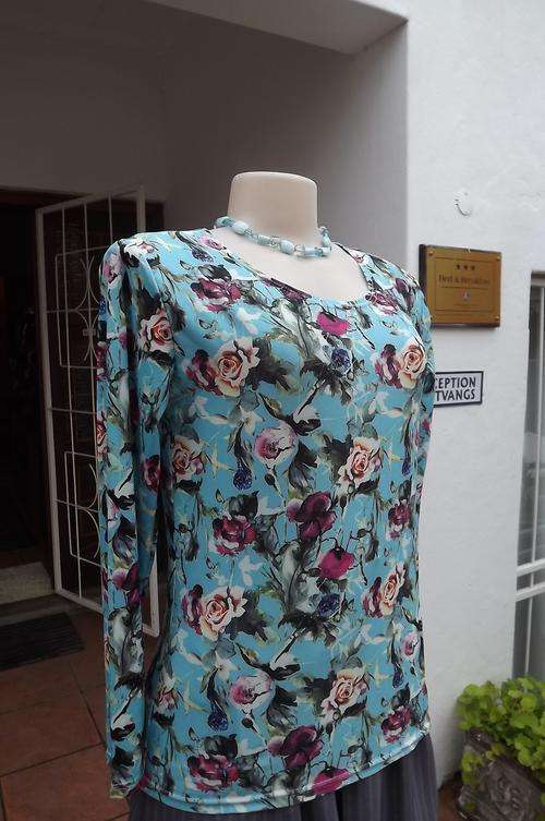 Sky blue polyester stretch long sleeve top with scattered purple pansies and other flowers.Size 38/1