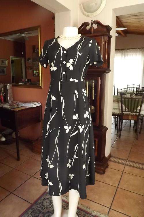 Pretty black A line dress with button down bust area.Size 32/8.Beige flower pattern.Paneled skirt.