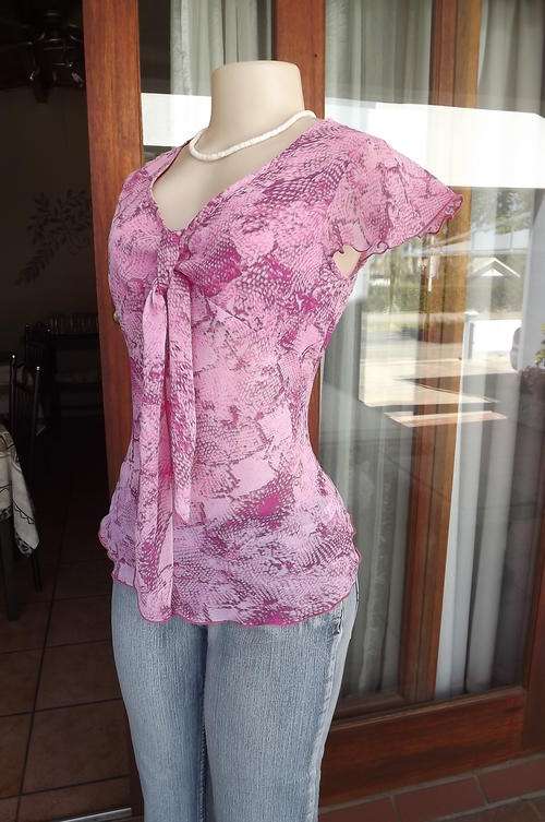 Feminine pink patterned top with capped sleeves and tie on front.Size 30/6.Can fit small 32 figure.