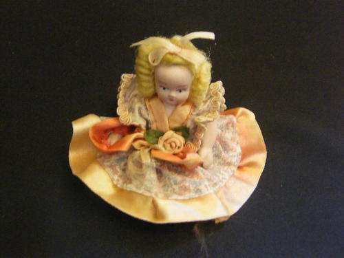 Small porcelain doll sitting as per photo