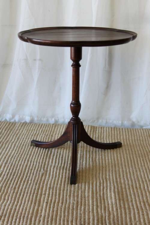 A MAGNIFICENT TEAK OCCASIONAL TABLE WITH BROAD RIMMED DETAILED TOP AND THREE BRASS TOE CAPS