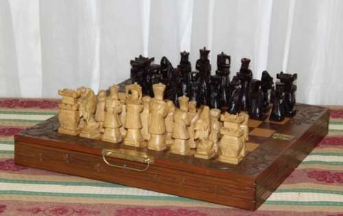 A SUPERB VINTAGE HAND-CARVED ORIENTAL FOLDING CHESS BOARD AND CARVED CHESS SET IN AWESOME CONDITION