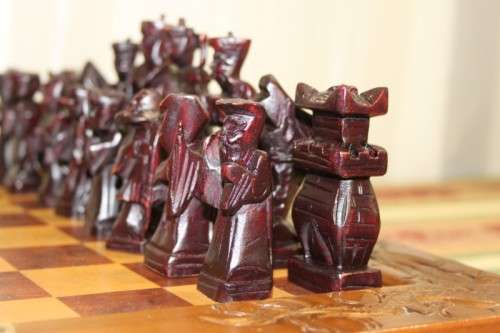 A SUPERB VINTAGE HAND-CARVED ORIENTAL FOLDING CHESS BOARD AND CARVED CHESS SET IN AWESOME CONDITION