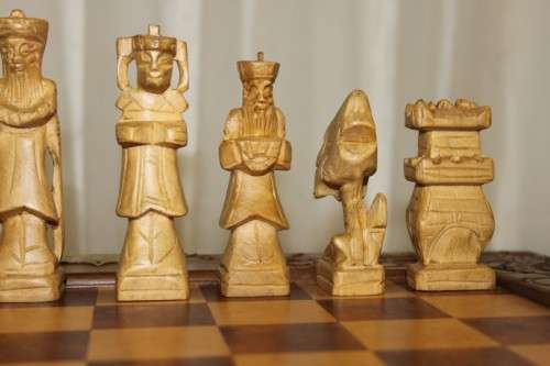 A SUPERB VINTAGE HAND-CARVED ORIENTAL FOLDING CHESS BOARD AND CARVED CHESS SET IN AWESOME CONDITION
