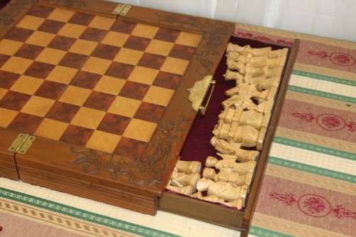 A SUPERB VINTAGE HAND-CARVED ORIENTAL FOLDING CHESS BOARD AND CARVED CHESS SET IN AWESOME CONDITION