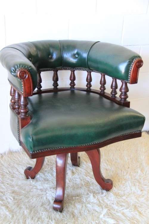 A spectacular solid mahogany "captain's swivel chair" with period British green upholstery