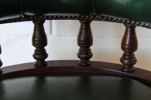 A spectacular solid mahogany "captain's swivel chair" with period British green upholstery