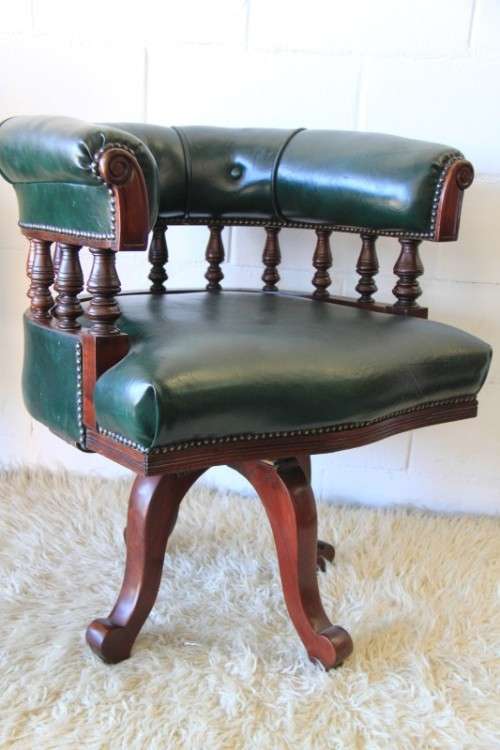A spectacular solid mahogany "captain's swivel chair" with period British green upholstery