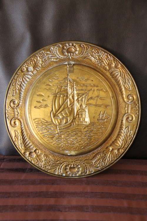A lovely vintage brass wall plate with a hand-embossed "ship" detailing and a wall hook on the back