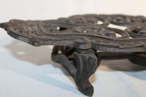 A cast iron pot warmer with space for two tealight candles, something special for dinner parties