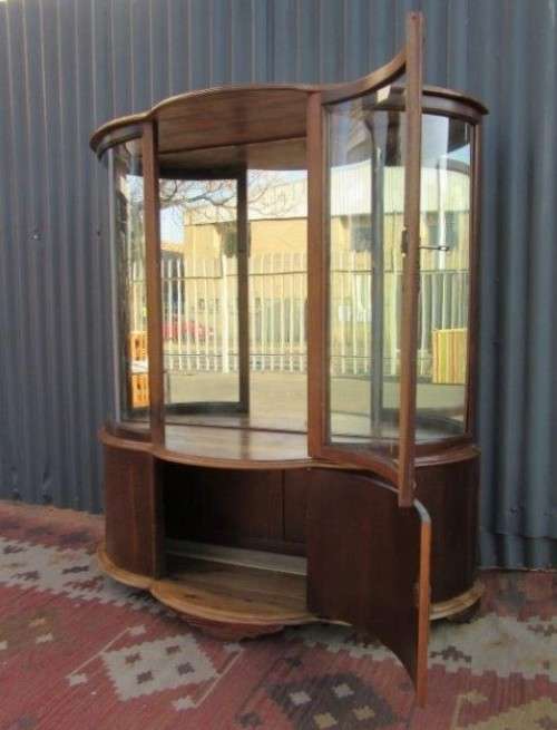 A stunning and beautifully made curved glass Teak show cabinet with solid brass embellishments