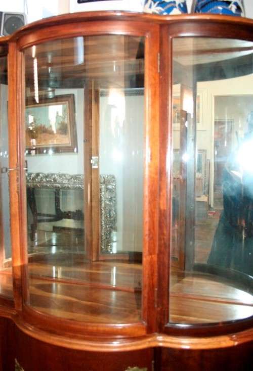A stunning and beautifully made curved glass Teak show cabinet with solid brass embellishments