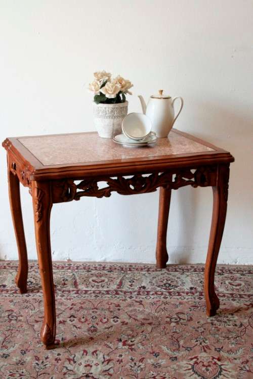 A wonderful and stylish teak side table with a marble top and beautifully carved detailing