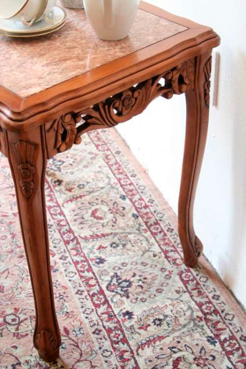 A wonderful and stylish teak side table with a marble top and beautifully carved detailing