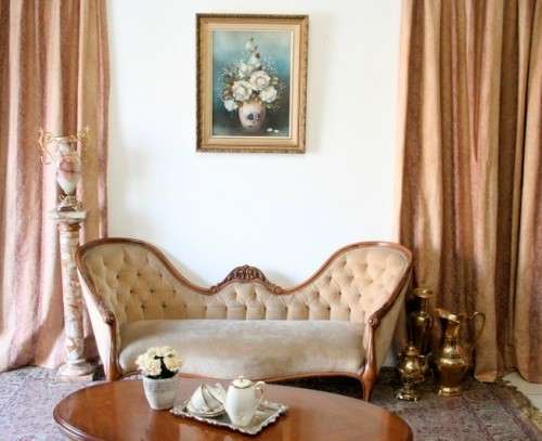 A beautiful, elegant carved Victorian sofa with deep button detailing and beige fabric.