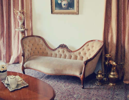 A beautiful, elegant carved Victorian sofa with deep button detailing and beige fabric.
