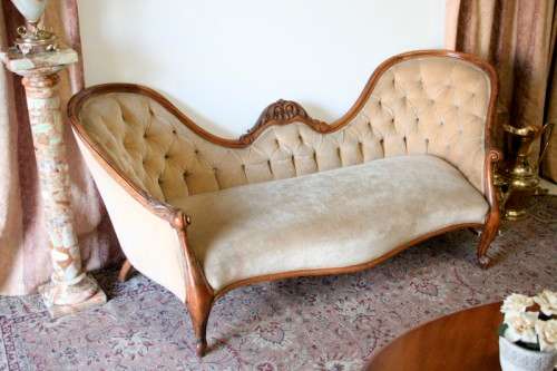 A beautiful, elegant carved Victorian sofa with deep button detailing and beige fabric.