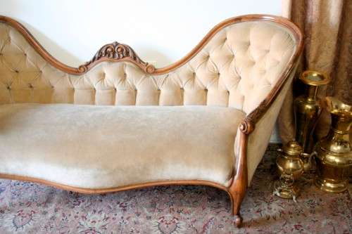 A beautiful, elegant carved Victorian sofa with deep button detailing and beige fabric.
