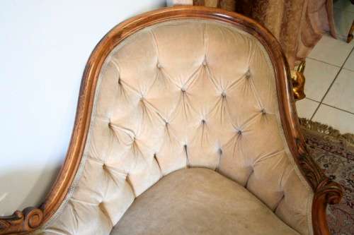 A beautiful, elegant carved Victorian sofa with deep button detailing and beige fabric.