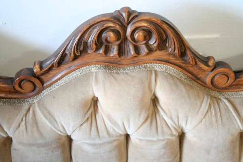 A beautiful, elegant carved Victorian sofa with deep button detailing and beige fabric.