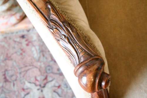 A beautiful, elegant carved Victorian sofa with deep button detailing and beige fabric.