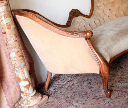 A beautiful, elegant carved Victorian sofa with deep button detailing and beige fabric.